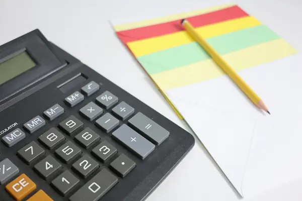 Calculator next to a notepad and pencil, representing the math behind a cash offer on a house