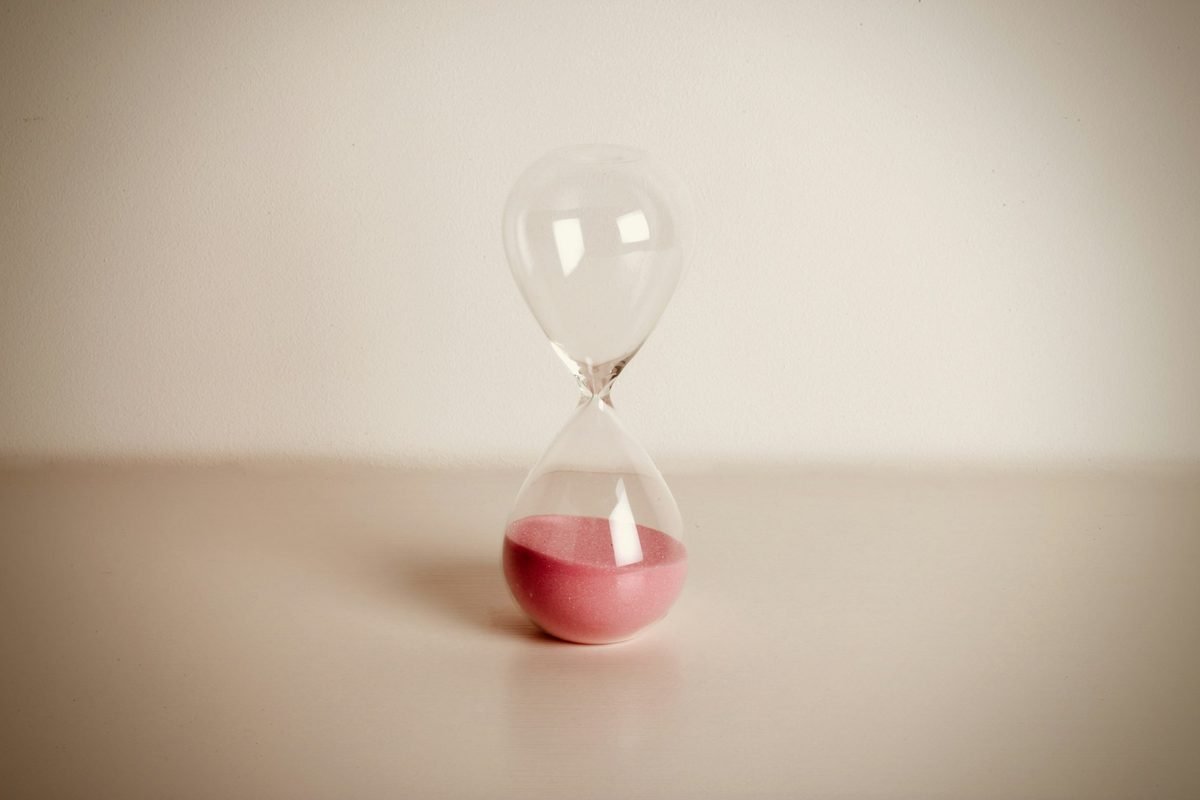 Hourglass with red sand running out, symbolizing the short Texas foreclosure timeline